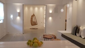 Un interior moderno con una zona de comedor, una silla colgante y un espacio de descanso con cojines.