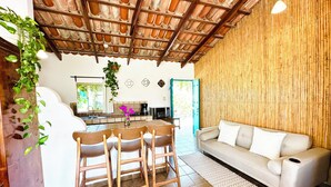 A modern kitchen with a dining area, a sofa, and a bamboo wall. - CABO BOHEMIA Tropical Garden Studios (Cabo San Lucas)