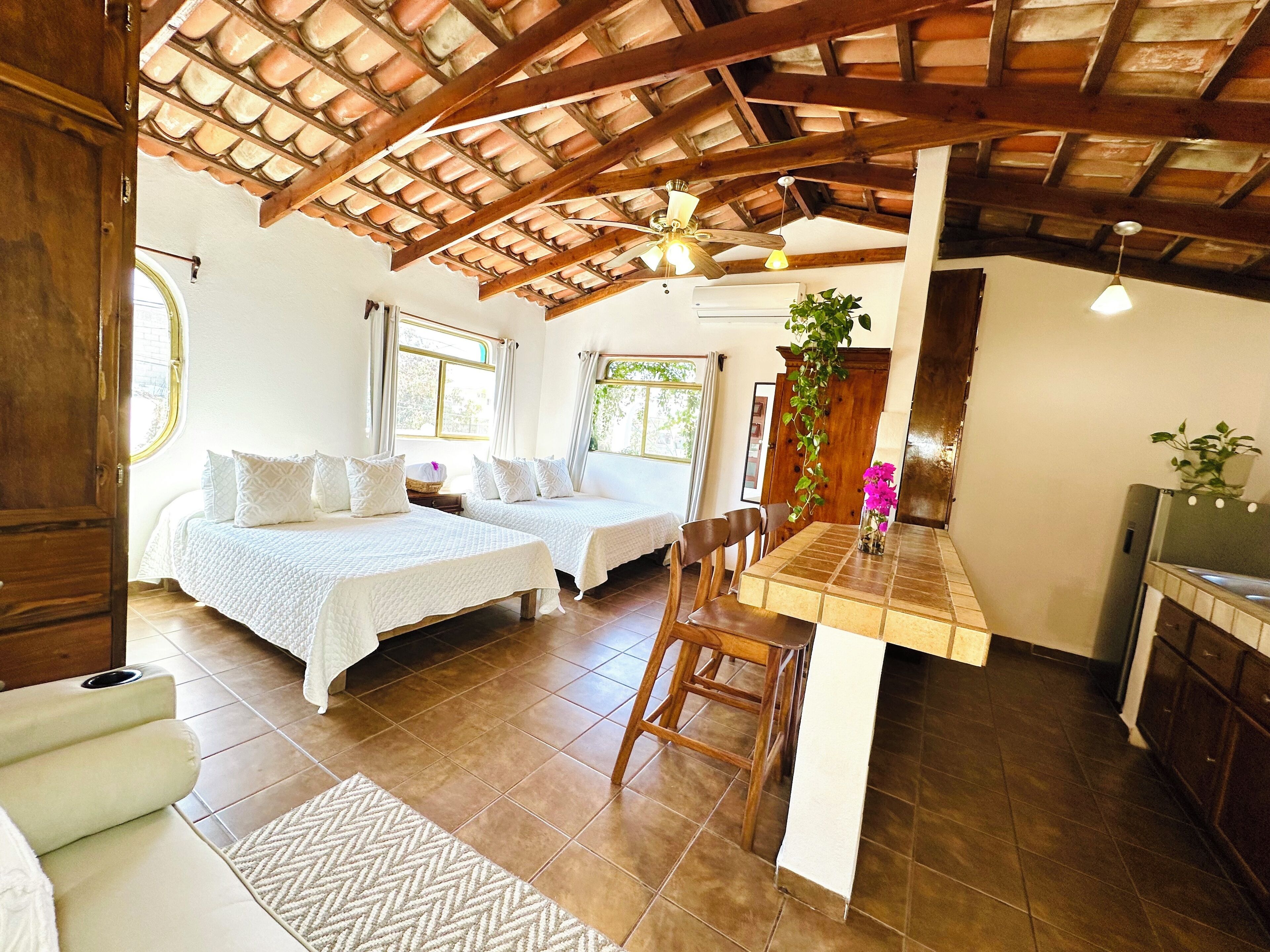A cozy room with two beds, a dining table, and a kitchen area.