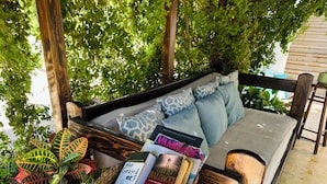 A wooden bench with a woven basket containing magazines and a book. - CABO BOHEMIA Tropical Garden Studios (Cabo San Lucas)