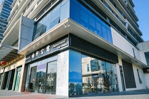 En moderne bygning med en glasfacade, en markant indgang og skilte, der angiver, at det er et hotel.