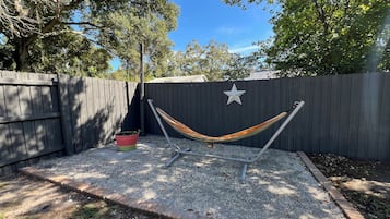 A hammock between two metal poles, a star decoration on a fence, and a potted plant.