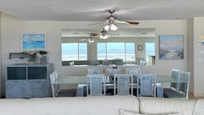 A spacious living area with a large dining table, multiple chairs, a sofa, and a ceiling fan.