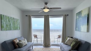 A living room with two sofas, a ceiling fan, and a view to the outside.