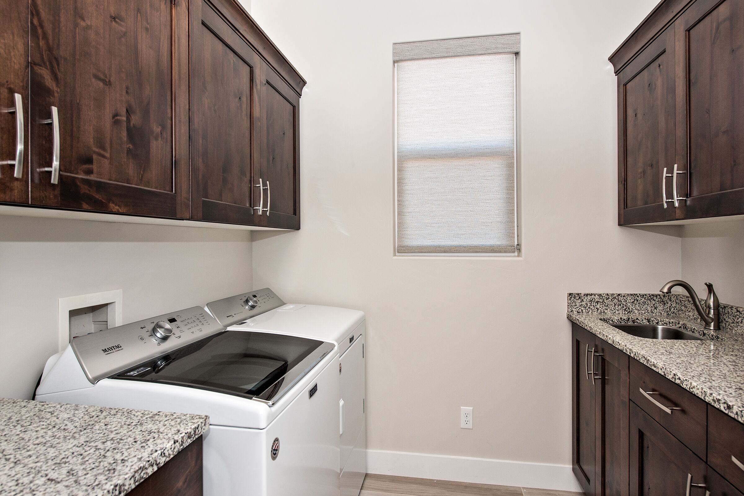 A kitchen with dark wooden cabinets, a built-in stove, a sink, and granite countertops.