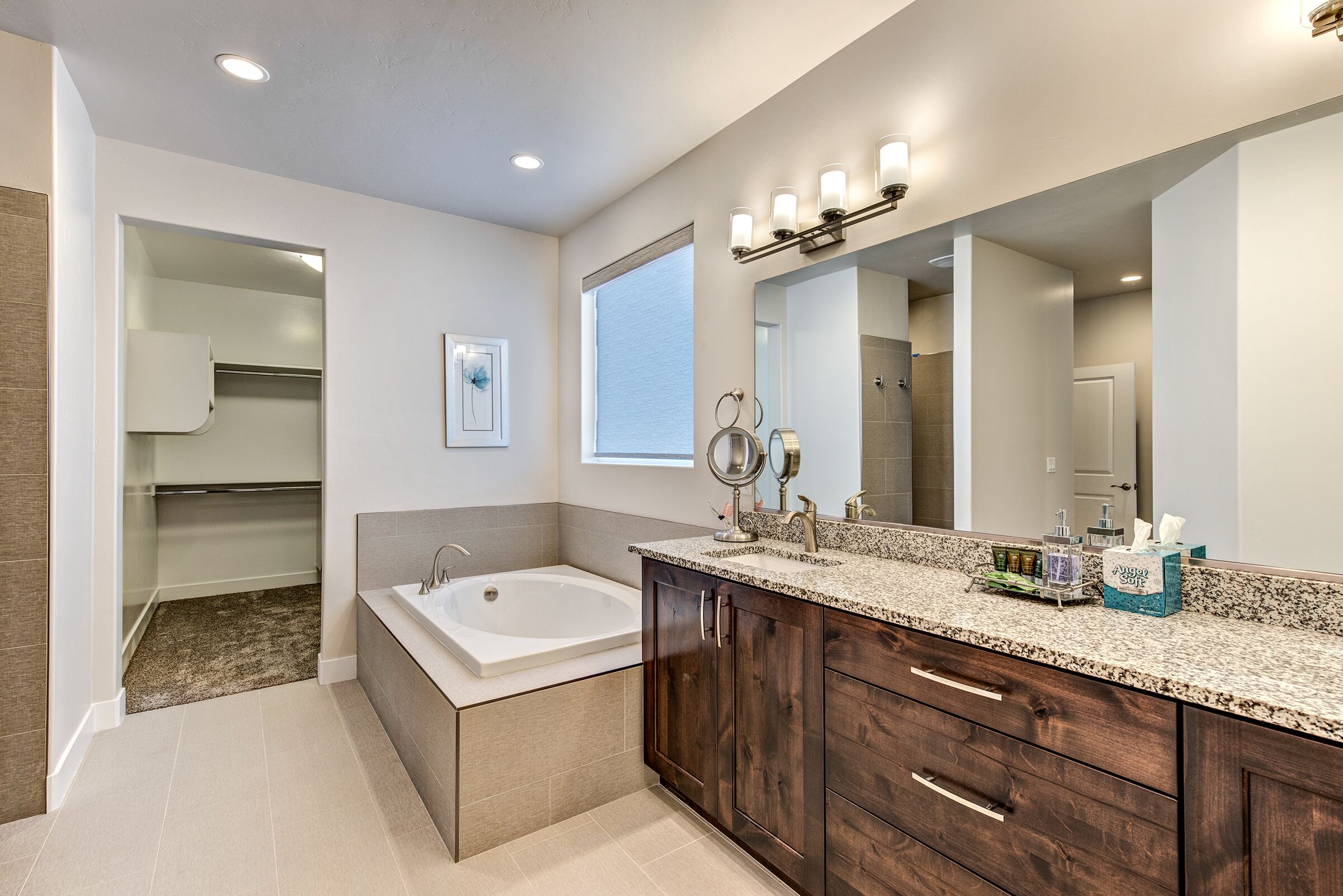 A modern bathroom with a freestanding bathtub, a vanity with a large mirror, and a walk-in shower.