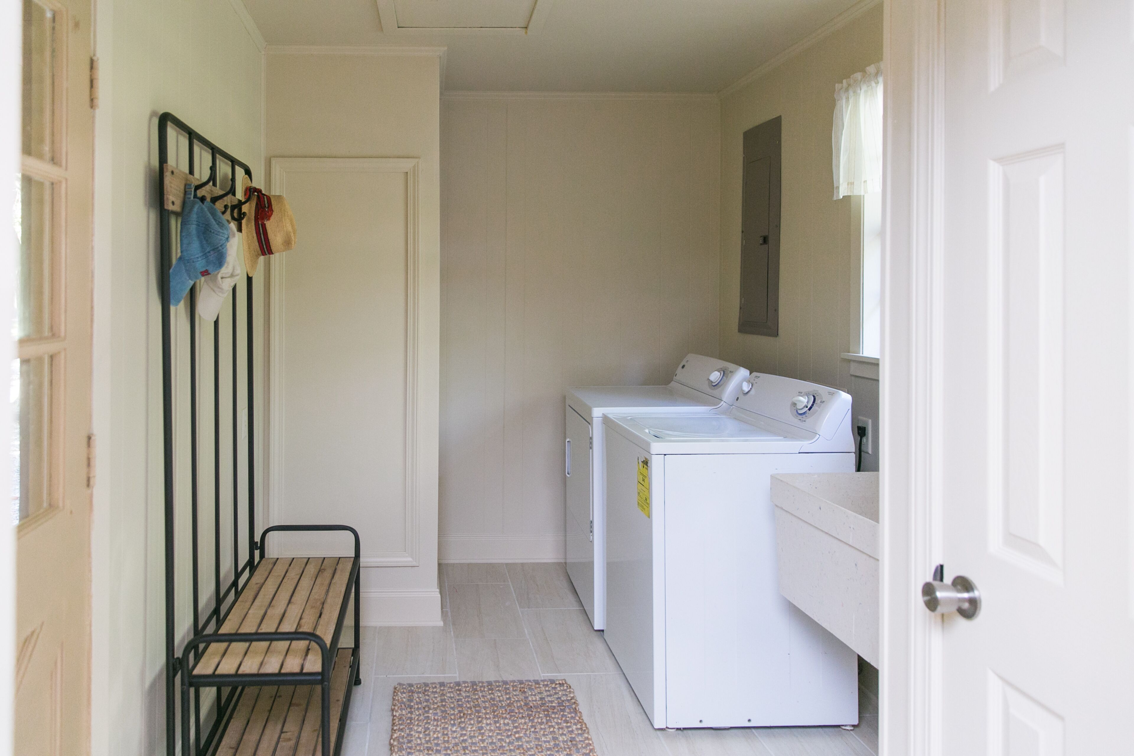 A laundry room with a bench, a washing machine, and a dryer.