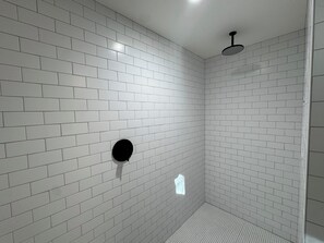 A modern shower with white tiles and a black circular feature on the wall. - Piety Hill Cottages (Nevada City)