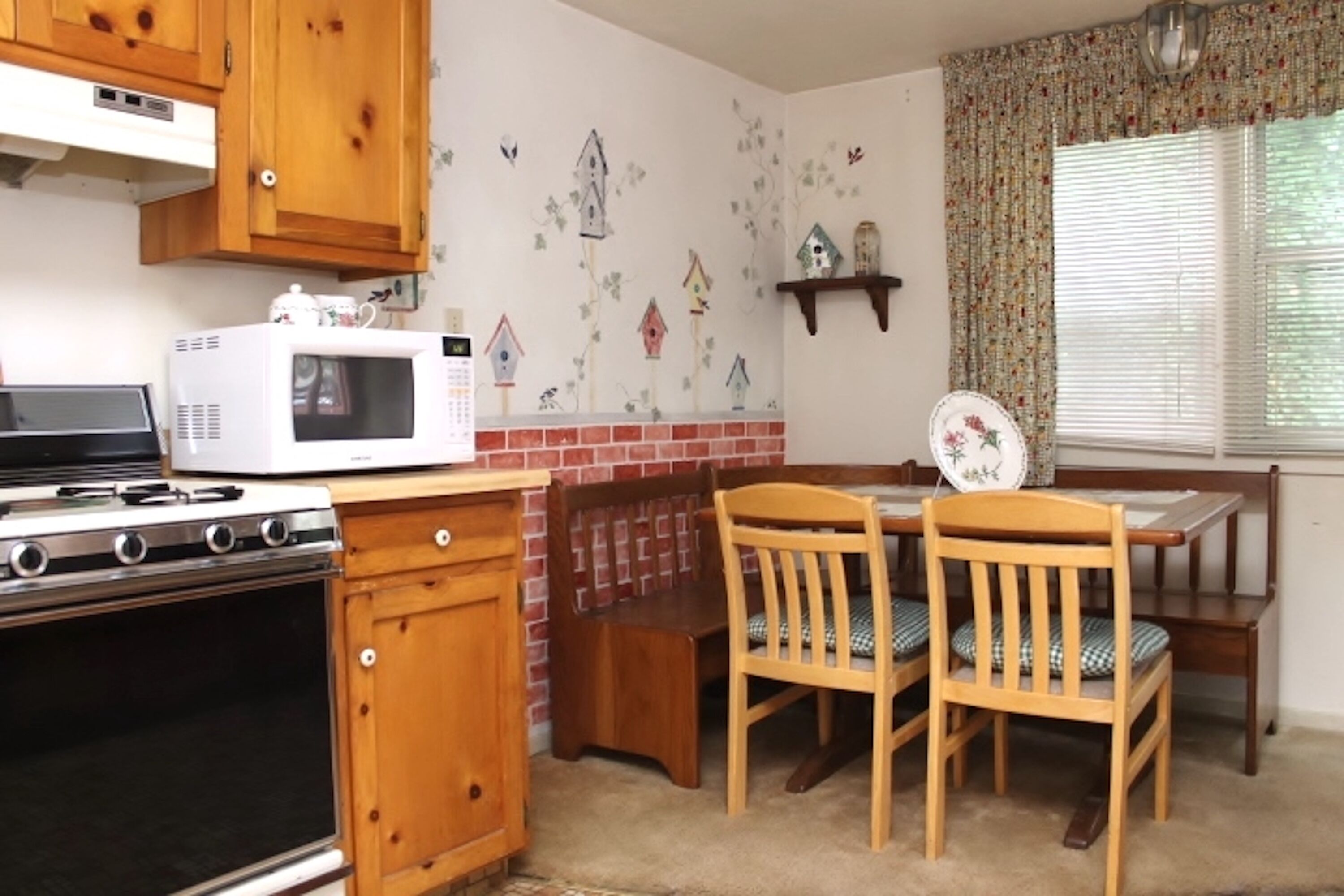 A kitchen with wooden cabinets, a microwave, a stove, and a dining table with chairs.