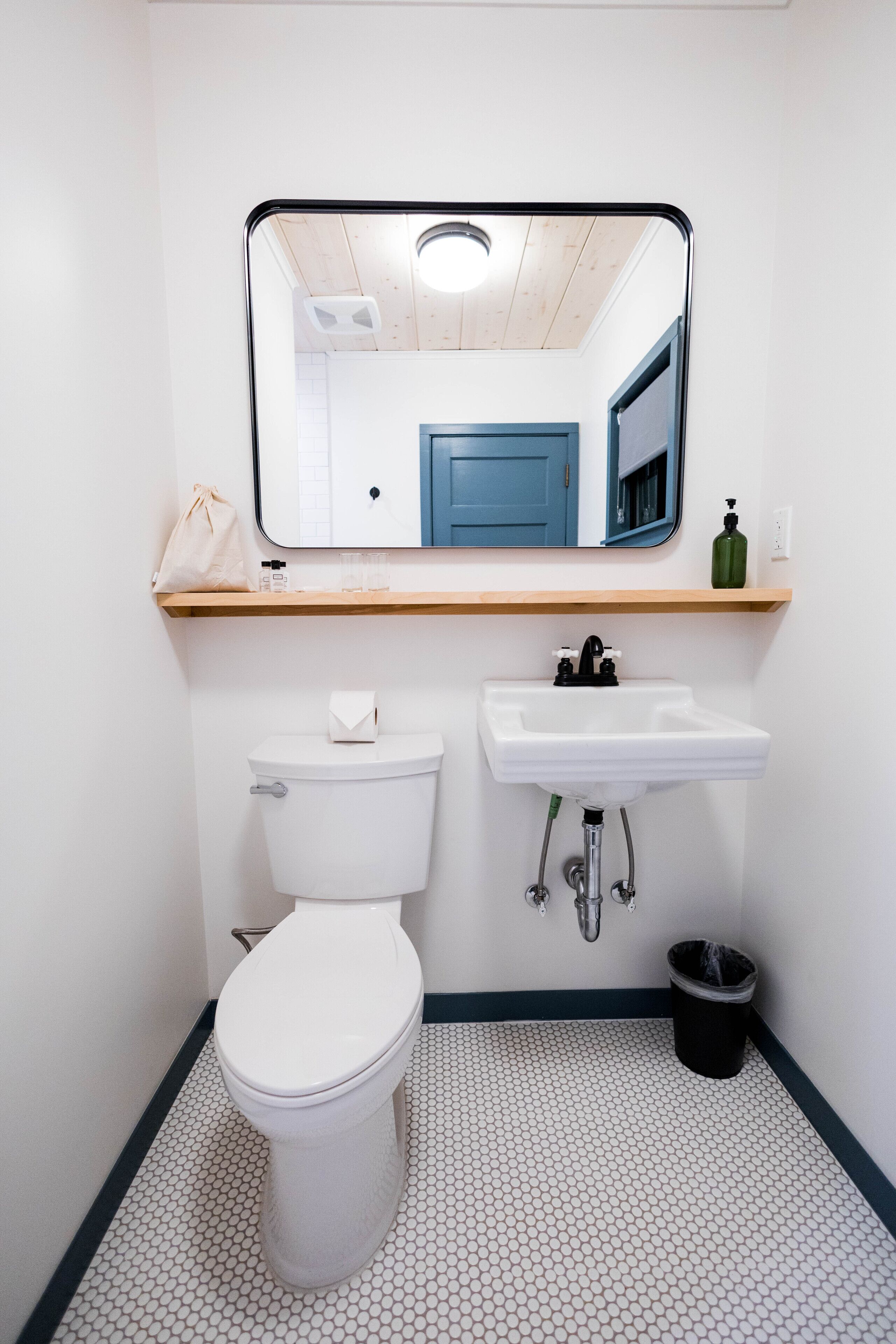 Ein kleines, sauberes Badezimmer mit Toilette, Waschbecken und Spiegel.