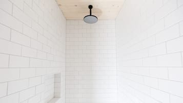 Una ducha estrecha con paredes de baldosas blancas, techo de madera y ducha de color negro.