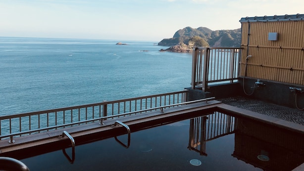 A pool area with a view of the sea and a wooden building. - Hotel Shiroitodai (Minami)