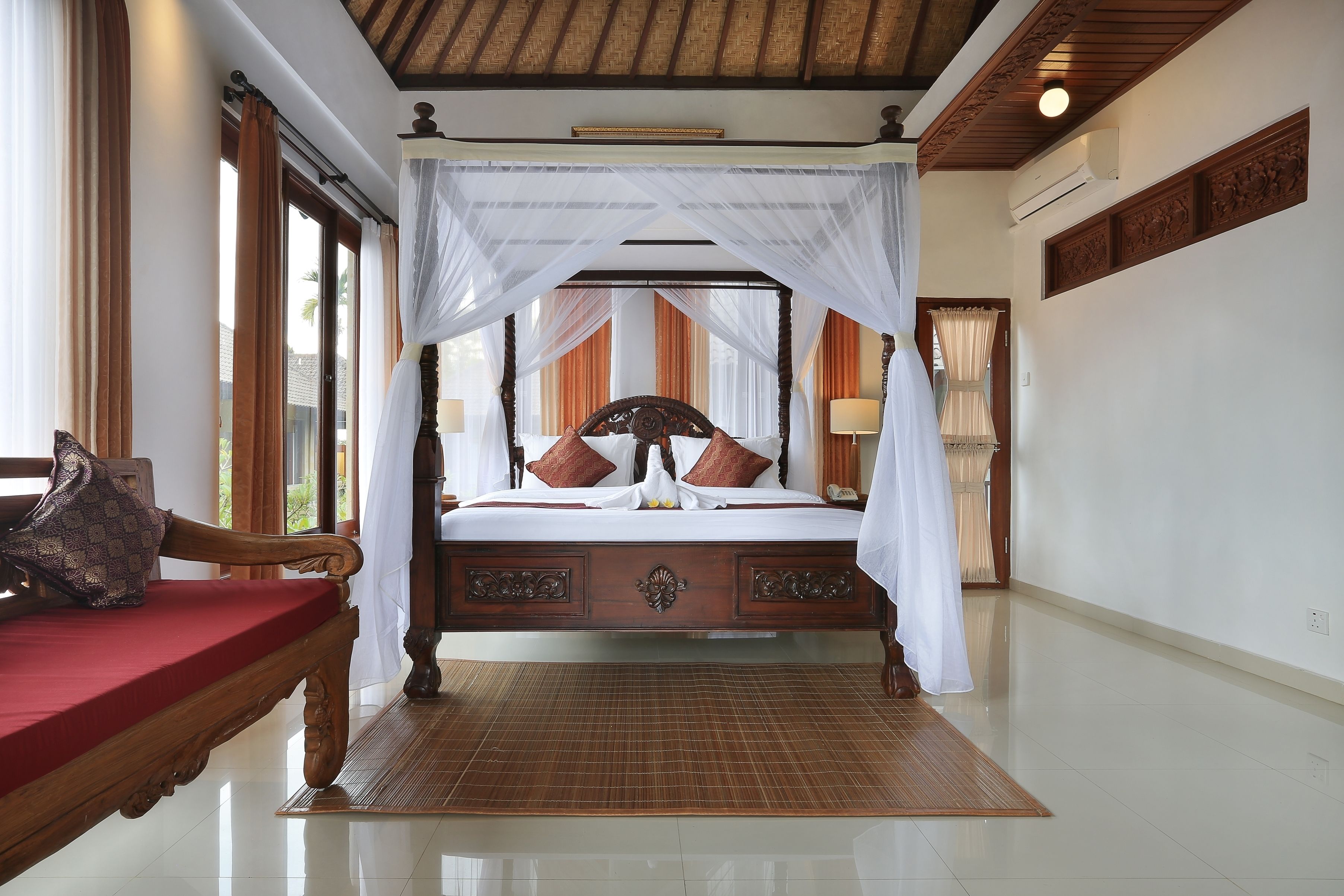 Un dormitorio amplio con una cama grande, un banco de madera y vistas al exterior.