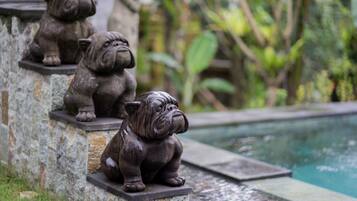 Three stone dog statues by a poolside.