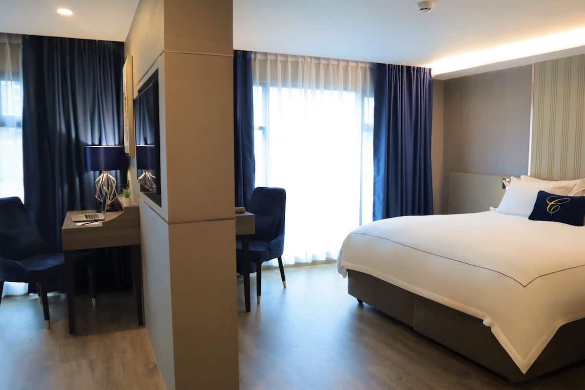 A hotel room with a large bed, a desk with a laptop, and a chair.