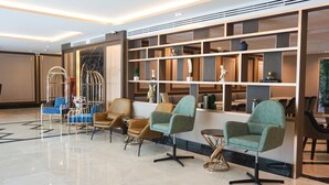 A lobby with modern seating, a reception desk, and a decorative wall with shelves. - GLOW Sukhumvit 5 by Centropolis (Bangkok)