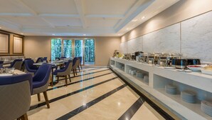 A modern dining area with a long counter, blue chairs, and a marble floor. - GLOW Sukhumvit 5 by Centropolis (Bangkok)