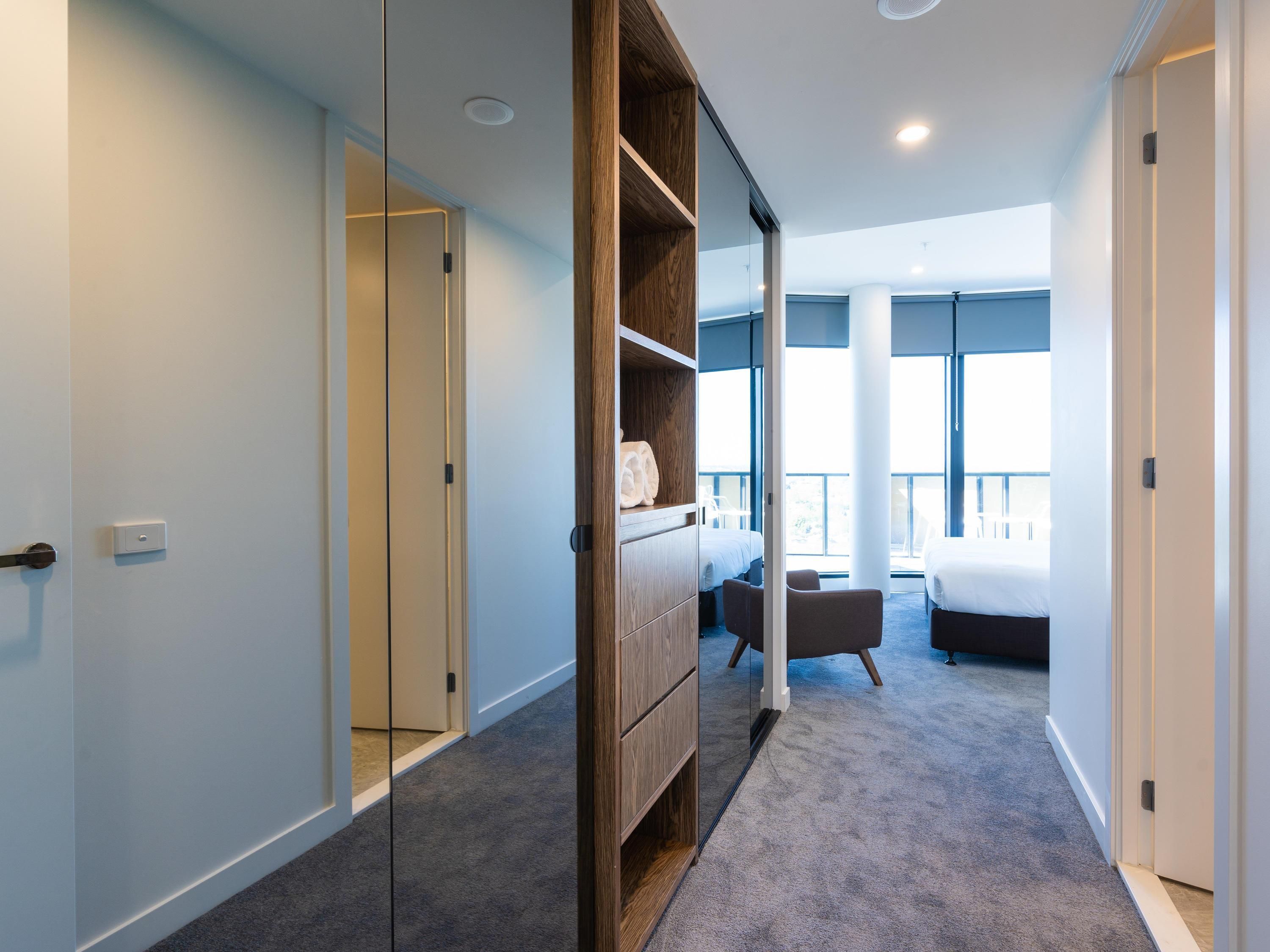 Habitación de hotel con armario, cama, zona de estar y vistas al exterior.