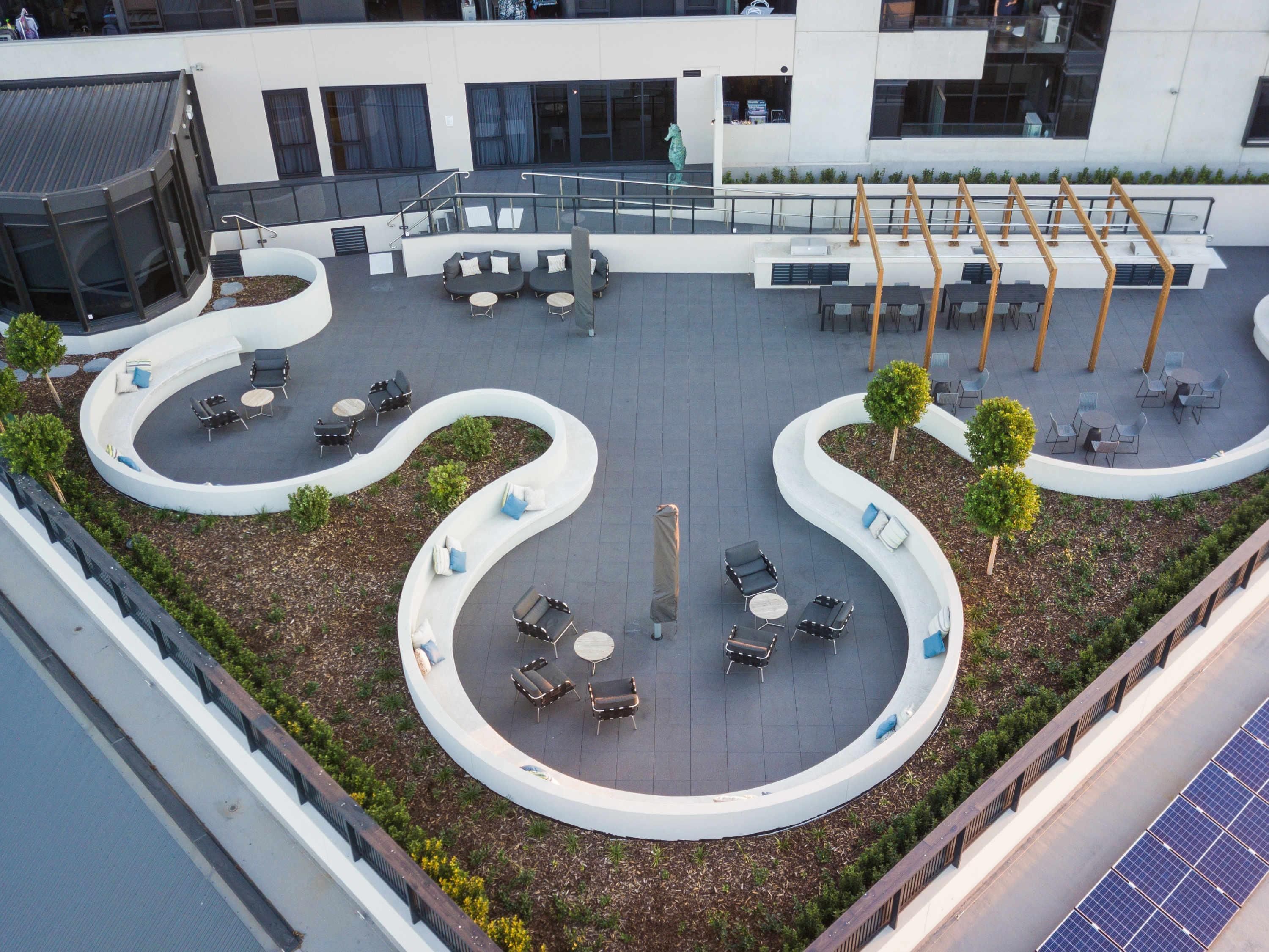 Eine Dachterrasse mit Außenbereich, Sitzgelegenheiten, einer Statue und Solaranlagen.