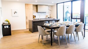 Un comedor moderno con una encimera de mármol, armarios de madera y un amplio ventanal con vistas.