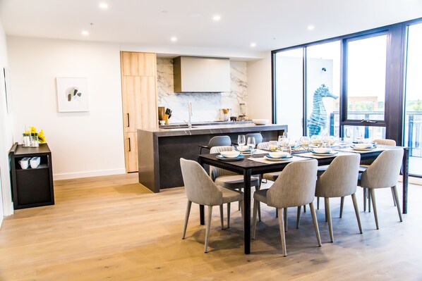 A modern dining area with a marble backsplash, wooden cabinets, and a large window offering a view. - The Sebel Melbourne Malvern (Malvern East)