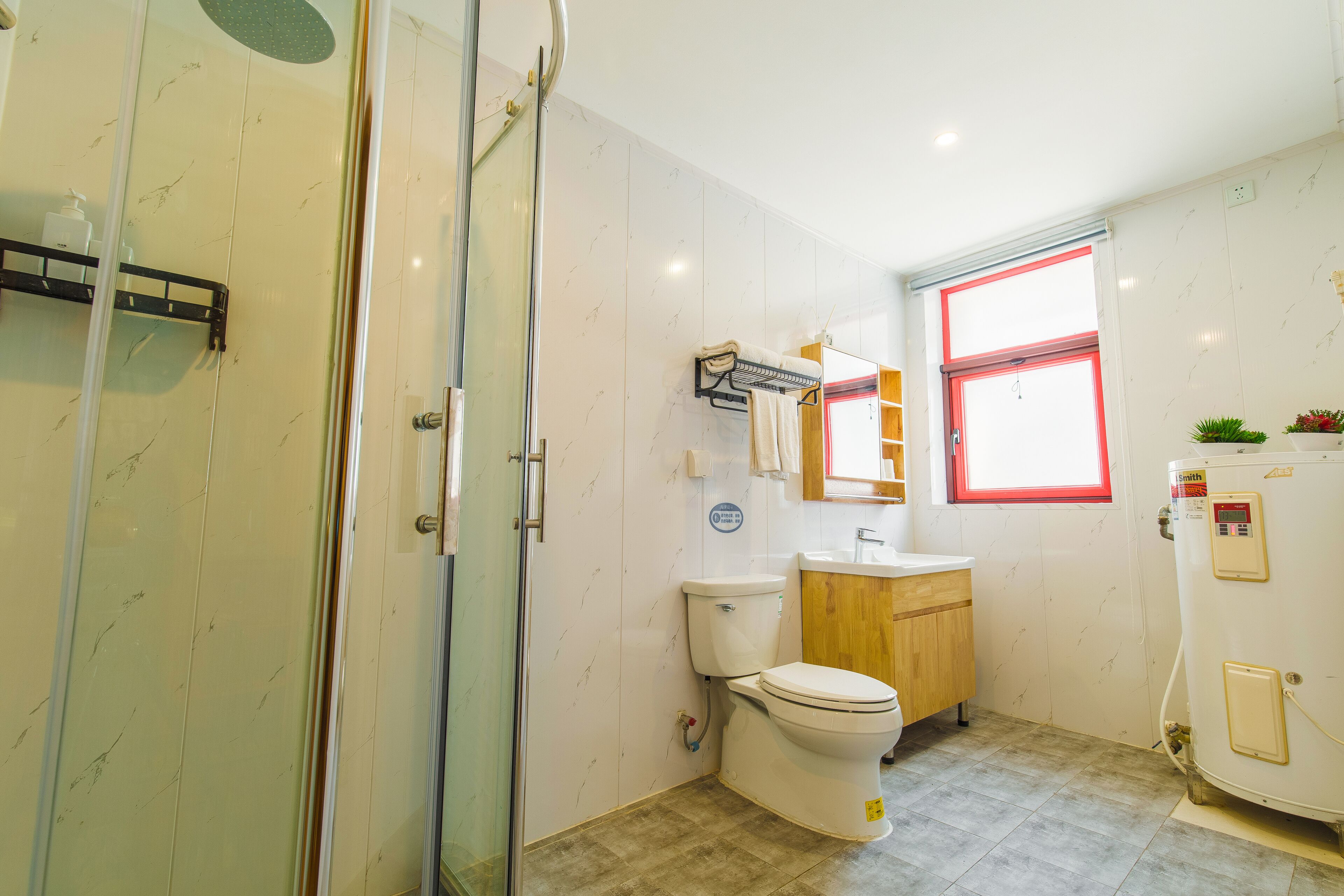 A bathroom with a glass shower enclosure, a toilet, a sink, and a heater.