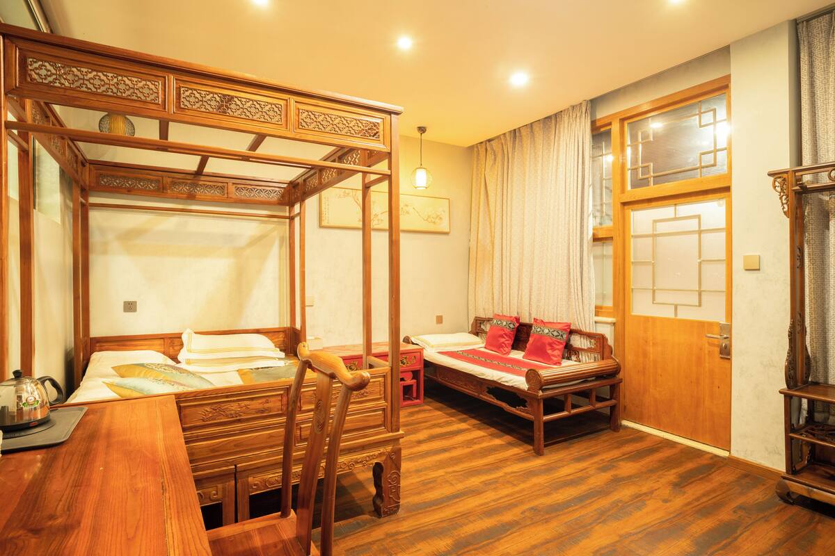 A traditional Japanese-style room with a tatami mat floor, a low wooden bed with a canopy, a small wooden table with a tea set, and a sliding door with a geometric pattern.