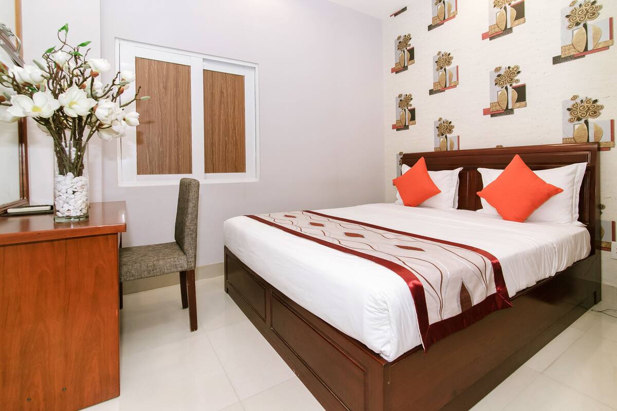 Un dormitorio ordenado con una cama, un escritorio y una silla.