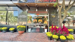 The exterior of Hotel Long Bảo Chánh, featuring a clear entrance with potted plants and a welcoming sign. - Long Bao Chau Hotel (Ho Chi Minh City)
