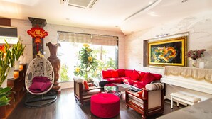 A modern living room with a red sofa, a white chair, a glass coffee table, and a piano. - Long Bao Chau Hotel (Ho Chi Minh City)
