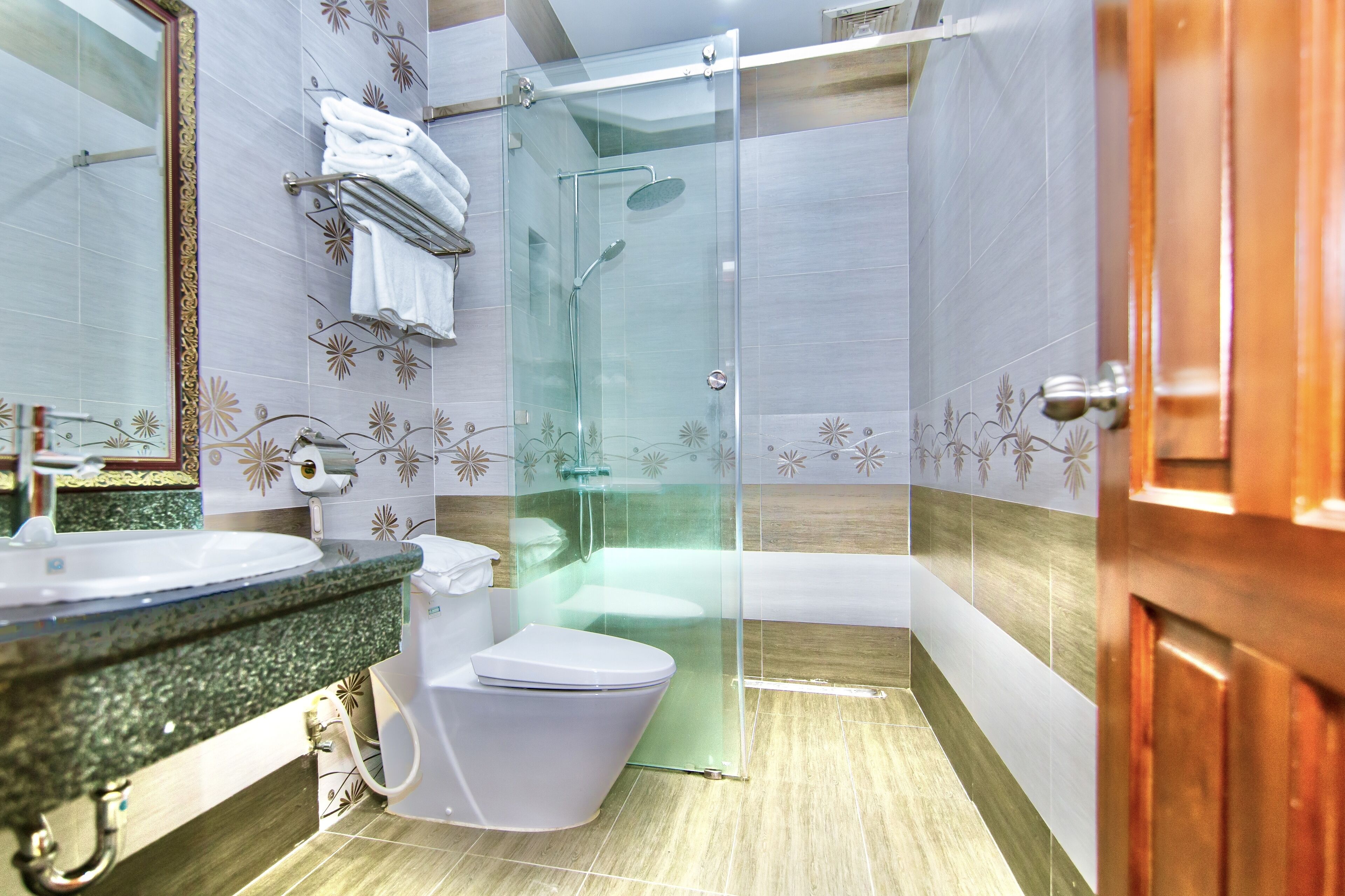 Une salle de bain avec une douche à parois de verre, des toilettes, un lavabo et un miroir.