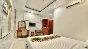 A hotel room with a bed, a desk, a chair, a television, and a wardrobe. - Long Bao Chau Hotel (Ho Chi Minh City)