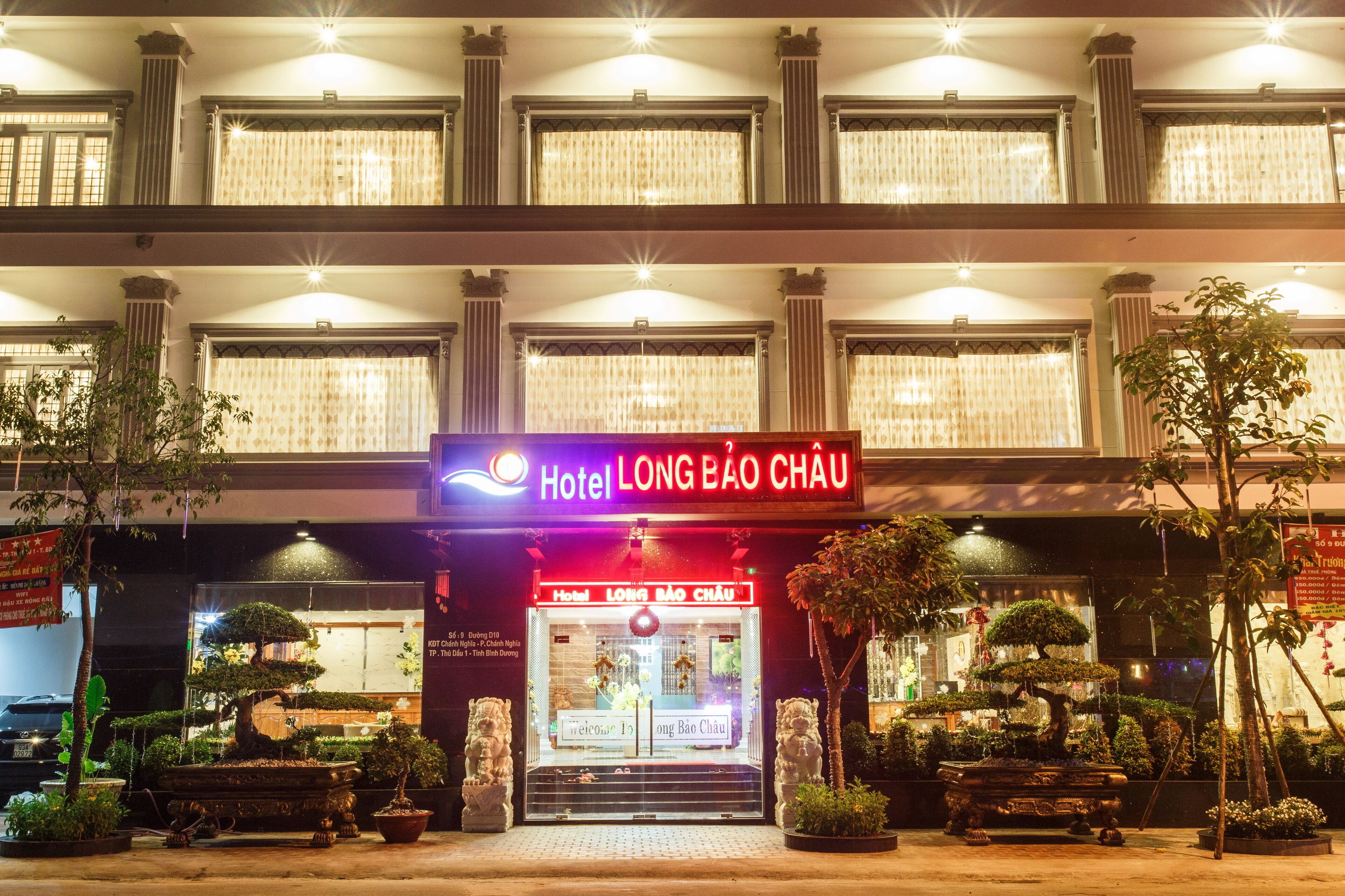 Hotel Long Báo Châu, con fachada tradicional, varios pisos y una entrada bien iluminada.