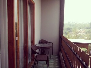 A balcony with a table and two chairs, a wooden railing, and a view of a residential area. - Casa De Apple (Bandung)