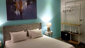 Une chambre d’hôtel avec un lit, une table de chevet, une lampe, une étagère et un tableau au mur.
