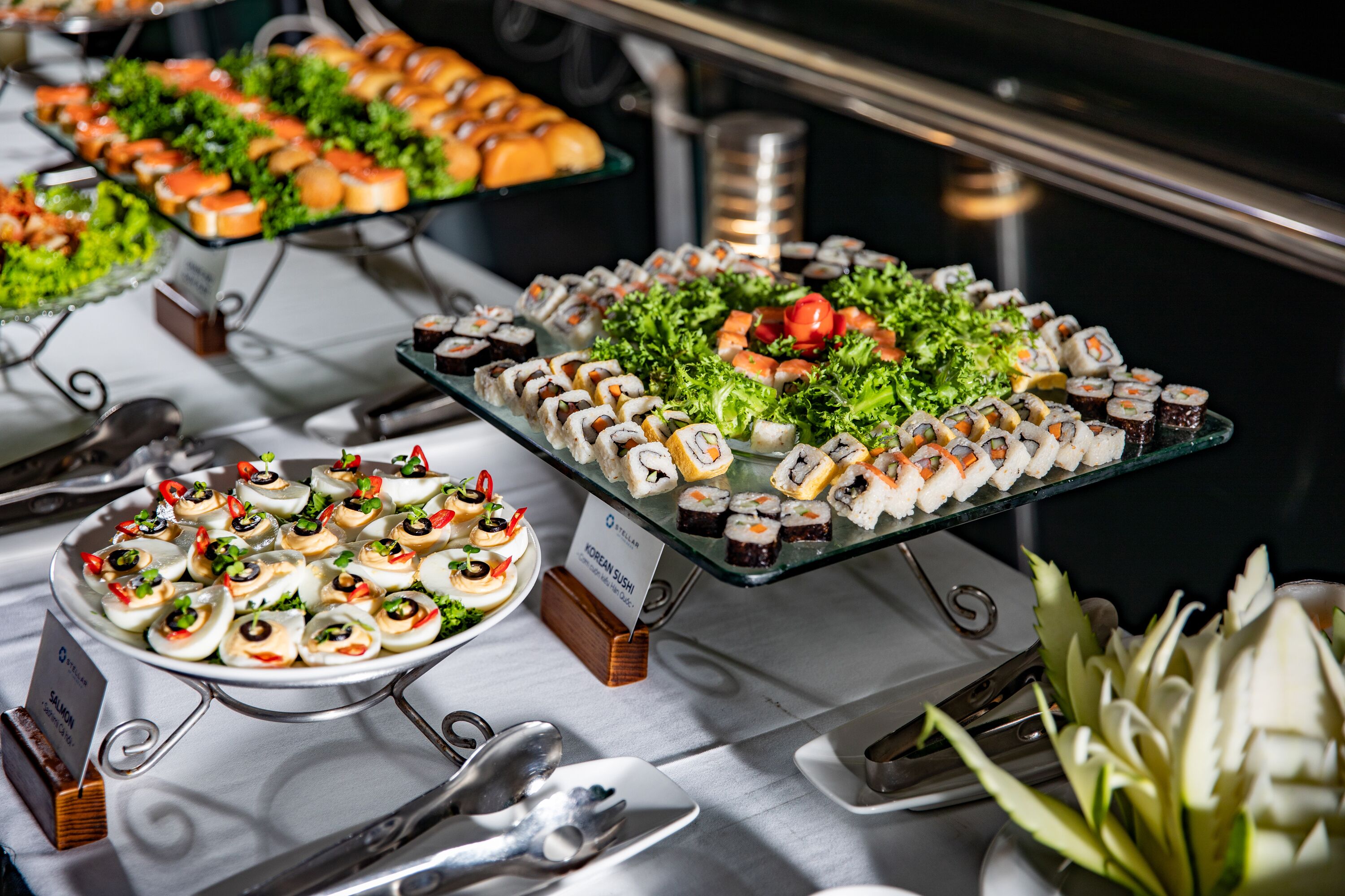 Un buffet proposant une variété de plats, notamment des sushis et des salades, présentés sur des plateaux de service en verre.