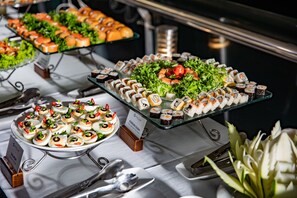 A buffet with various food items, including sushi and salads, arranged on glass serving platters. - Stellar of the Seas (Hanoi)