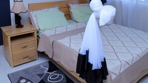A bedroom with a bed, nightstand, and a wall-mounted picture. - Floben Apartments (Kampala)