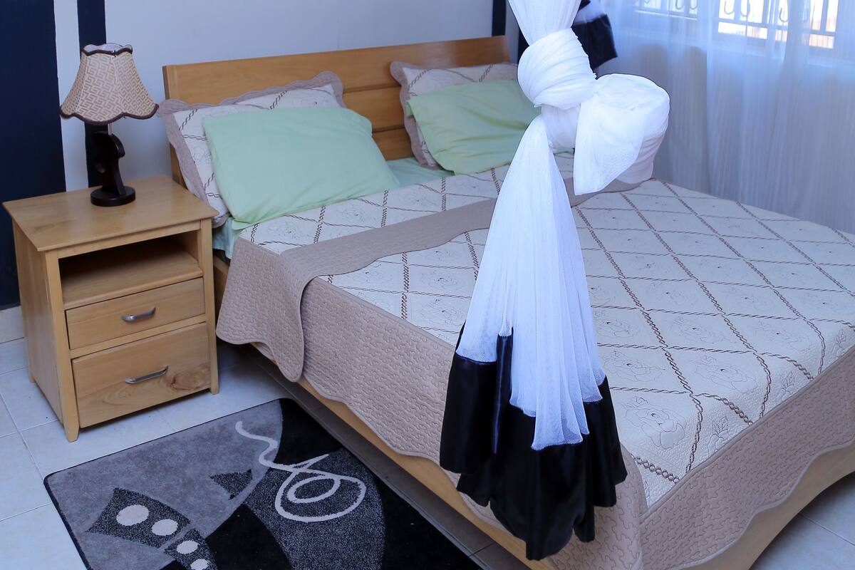 A bedroom with a bed, nightstand, and a wall-mounted picture.