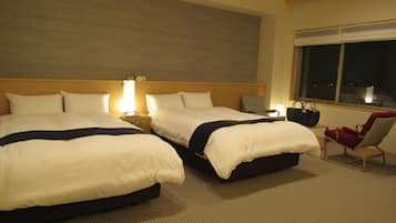 A hotel room with two beds, a nightstand with a lamp, a chair, and a view of the night sky through a window.