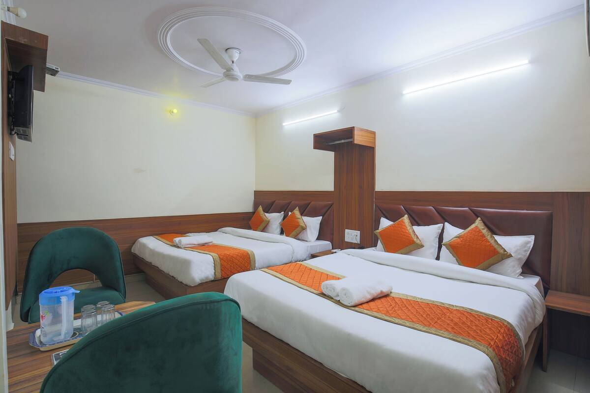 A hotel room with two beds, a ceiling fan, and a small table with a chair.