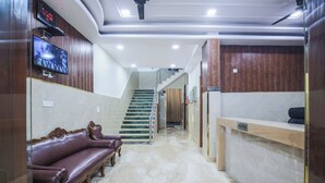 Un espace d’accueil doté d’un sol en marbre, d’un comptoir de réception, d’un escalier et de sièges en cuir.