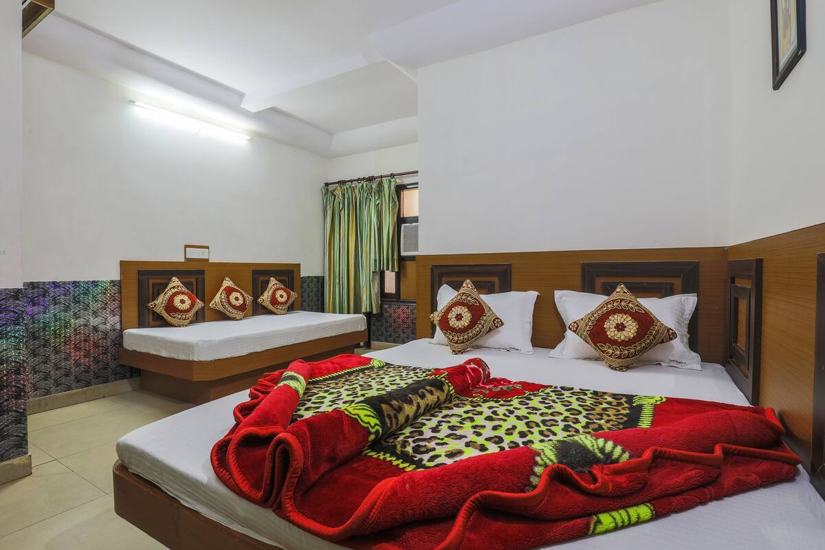 A hotel room with a bed, a smaller bed, and a window with curtains.