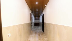 Un couloir doté d’un sol en marbre poli, d’un plafond en bois et de portes en verre donnant sur les pièces.