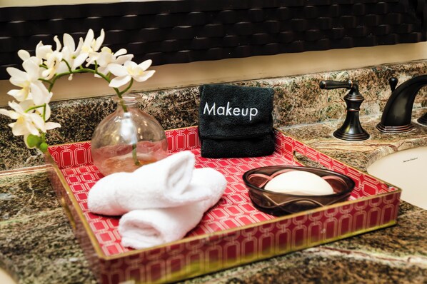 A bathroom vanity with a red patterned tray holding a white towel, a black towel labeled "Makeup," a glass vase with white flowers, and a soap dish. - Rare Find! Beachfront Villa w/ Private Pool, Hot Tub, Sauna & Breakfast Services (Tamarindo)