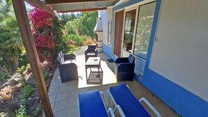 Un patio cubierto con sillones azules, una mesa y una silla.