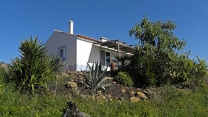 Una casa moderna con fachada blanca, una chimenea y un porche cubierto.