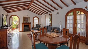A spacious living area with a wooden ceiling, a fireplace, a dining table with chairs, and a sofa. - GC0181 Holiday cottage in Valsequillo (Valsequillo)