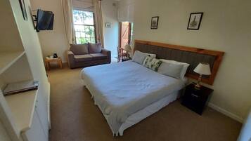 Habitación de hotel con una cama grande, un sofá, un televisor y un escritorio.