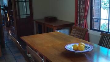 Una mesa de madera con un plato de limones y un bol, rodeada de sillas.